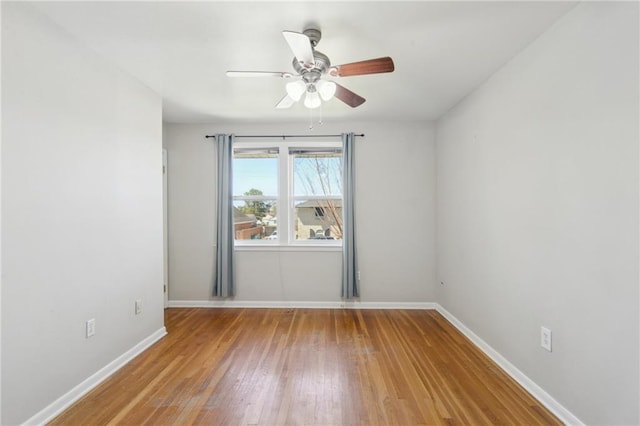 spare room with baseboards, wood finished floors, and ceiling fan