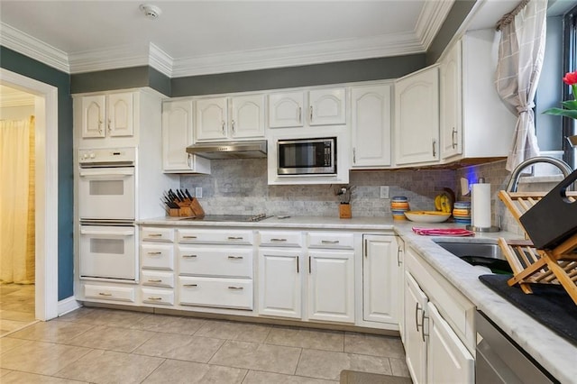 kitchen with under cabinet range hood, stainless steel appliances, light countertops, and white cabinetry