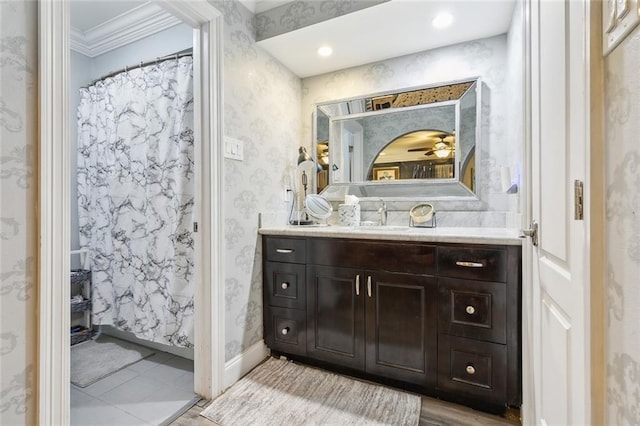 full bathroom featuring vanity, wallpapered walls, baseboards, and ornamental molding