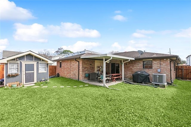 back of property featuring brick siding, a patio, an outbuilding, and central AC