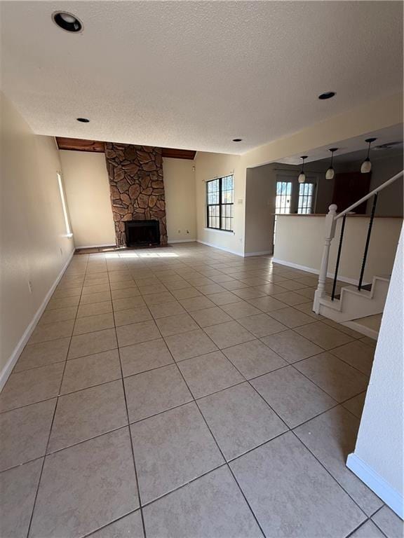 unfurnished living room featuring light tile patterned floors, baseboards, a textured ceiling, and a fireplace