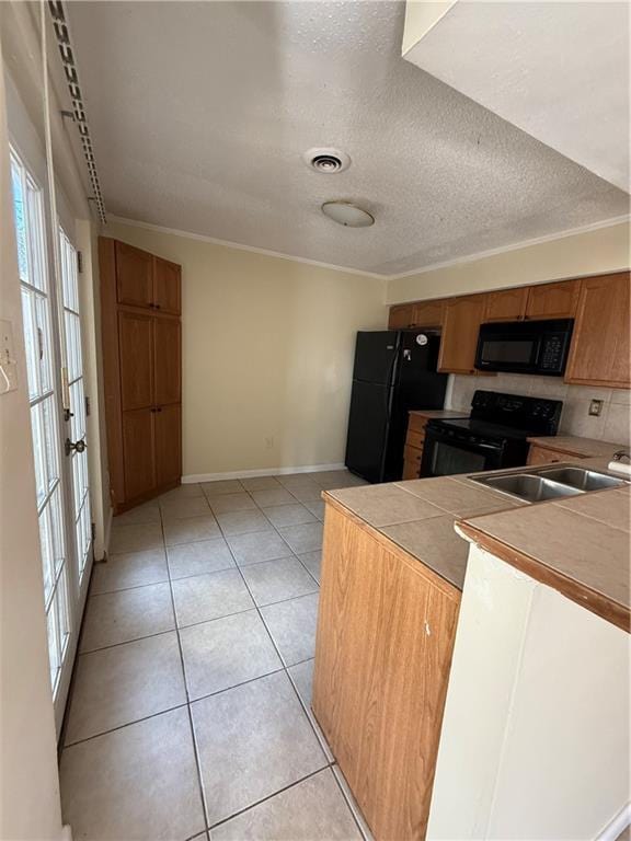 kitchen featuring visible vents, black appliances, light tile patterned floors, a textured ceiling, and a sink