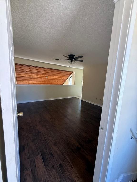 empty room featuring a ceiling fan, wood finished floors, baseboards, and a textured ceiling