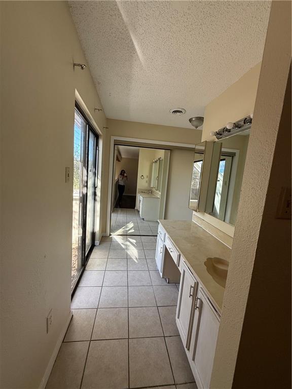 bathroom featuring tile patterned flooring, washing machine and dryer, a textured ceiling, and vanity