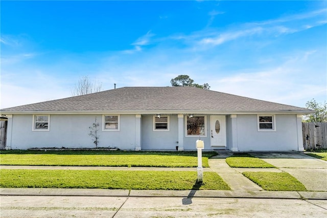 ranch-style home featuring a front lawn, fence, roof with shingles, and stucco siding