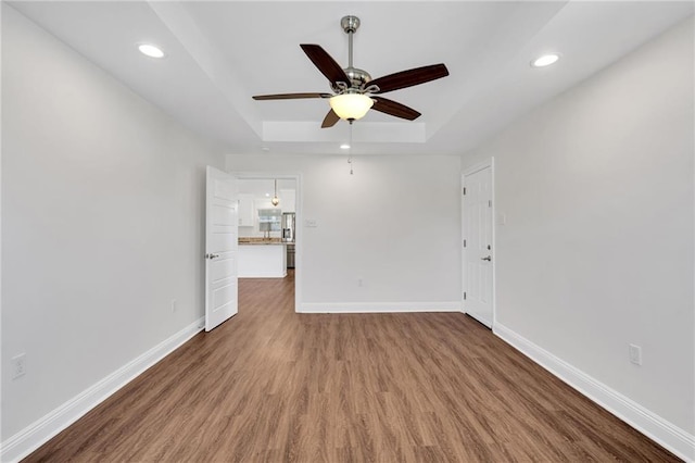 unfurnished room with recessed lighting, baseboards, a tray ceiling, and wood finished floors