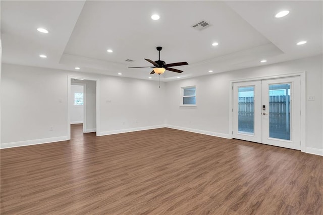 unfurnished room with recessed lighting, a tray ceiling, visible vents, and wood finished floors