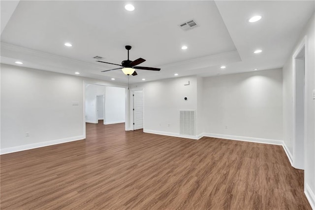 empty room with recessed lighting, visible vents, wood finished floors, and a tray ceiling