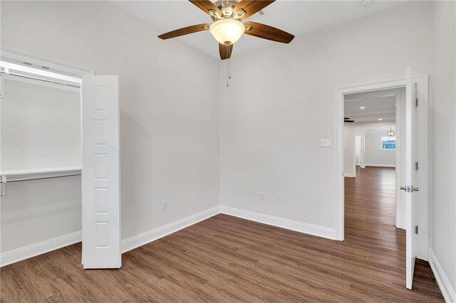 unfurnished bedroom with a closet, ceiling fan, baseboards, and wood finished floors