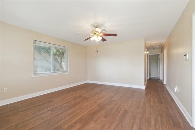 unfurnished room featuring ceiling fan, attic access, dark wood-type flooring, and baseboards