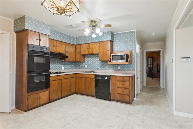 kitchen featuring under cabinet range hood, black appliances, brown cabinetry, and wallpapered walls