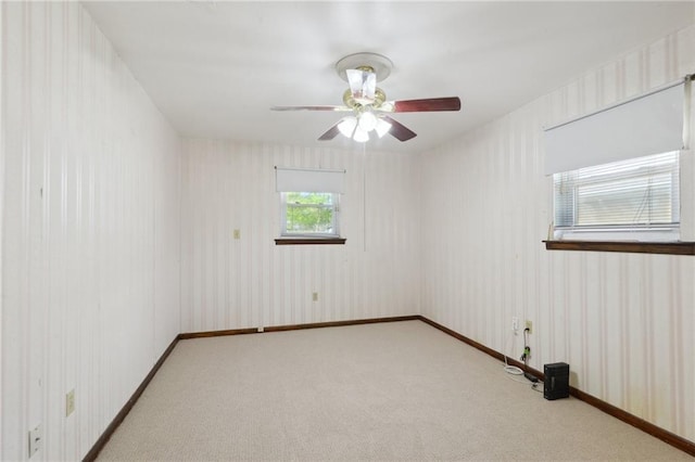 carpeted empty room featuring wallpapered walls, a ceiling fan, and baseboards