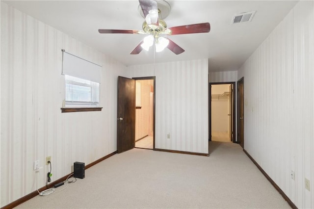 unfurnished bedroom featuring a spacious closet, visible vents, wallpapered walls, and carpet floors