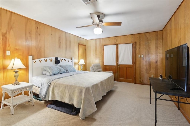 bedroom with visible vents, light carpet, ceiling fan, and wood walls