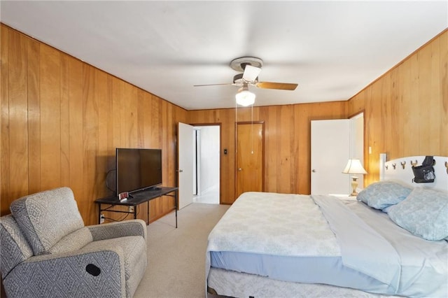 bedroom with ceiling fan, wood walls, and light carpet