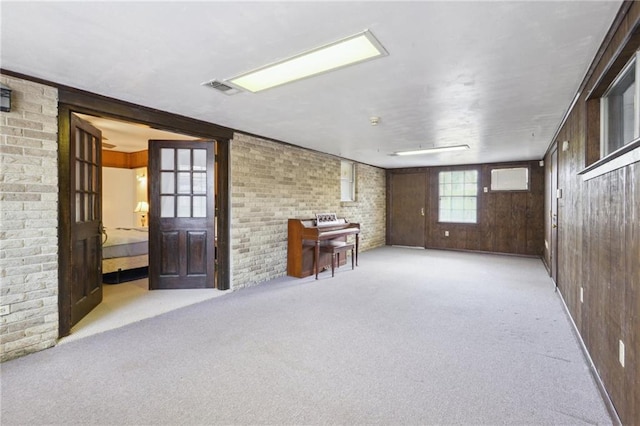 interior space with carpet, visible vents, and brick wall