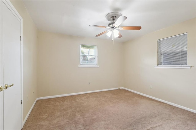 carpeted empty room featuring baseboards and ceiling fan