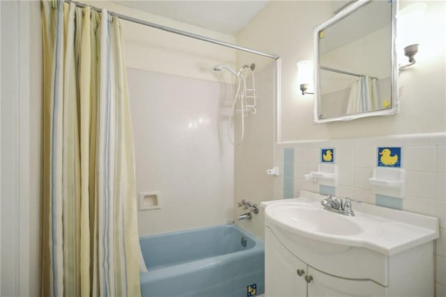 full bathroom with vanity, tile walls, a wainscoted wall, and shower / tub combo with curtain