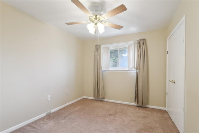 empty room with light colored carpet, baseboards, and ceiling fan