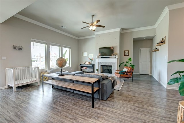 living room featuring a fireplace, crown molding, baseboards, and wood finished floors