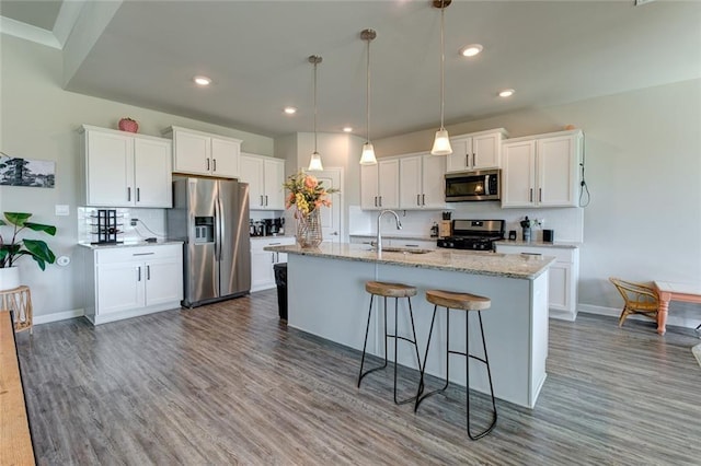 kitchen with dark wood-type flooring, a sink, tasteful backsplash, white cabinetry, and appliances with stainless steel finishes