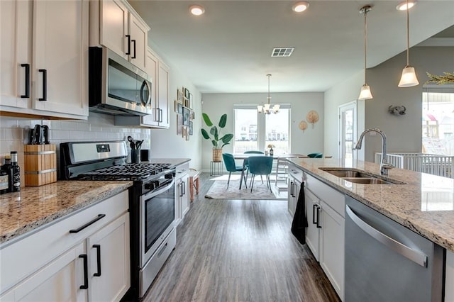 kitchen featuring tasteful backsplash, visible vents, a sink, appliances with stainless steel finishes, and dark wood-style flooring