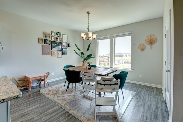 dining area with baseboards, a notable chandelier, and wood finished floors