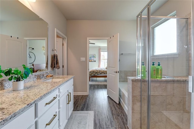 full bathroom with wood finished floors, vanity, a stall shower, and ensuite bathroom