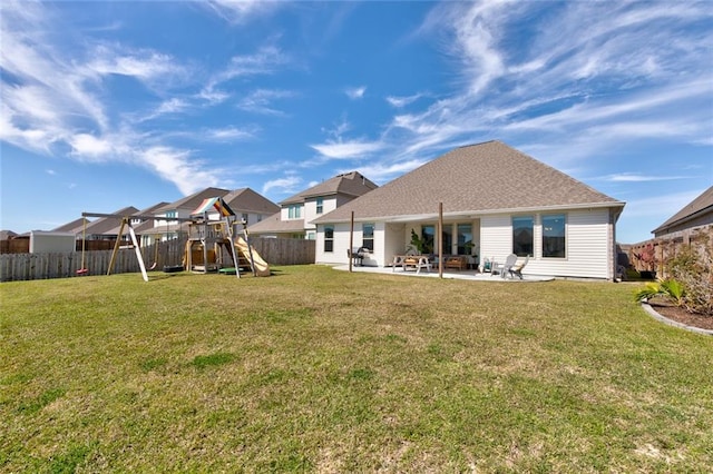 back of house featuring a yard, a playground, a fenced backyard, and a patio area