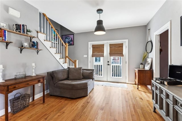 foyer entrance with french doors, baseboards, light wood-style flooring, and stairs