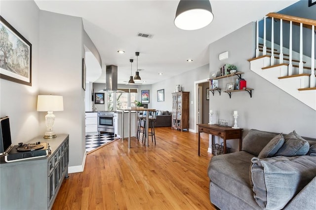 living room with visible vents, baseboards, stairway, recessed lighting, and light wood-style flooring