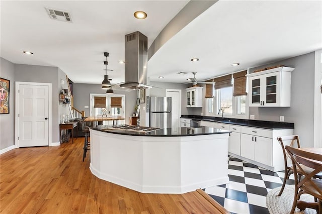 kitchen with visible vents, a sink, appliances with stainless steel finishes, island range hood, and light floors