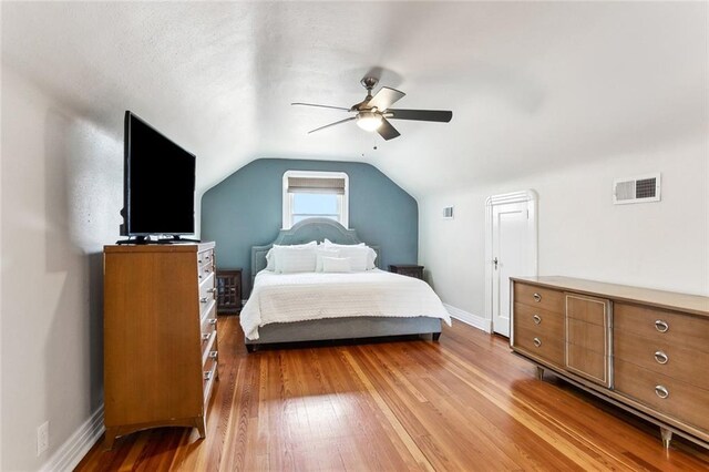 bedroom featuring a ceiling fan, visible vents, baseboards, lofted ceiling, and light wood-style floors