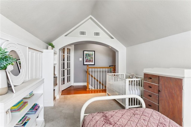 carpeted bedroom featuring vaulted ceiling, baseboards, visible vents, and arched walkways