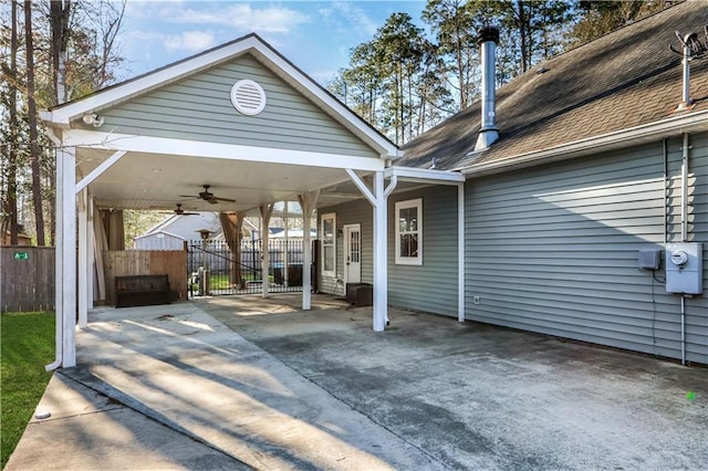 view of car parking with a ceiling fan, a carport, fence, and driveway