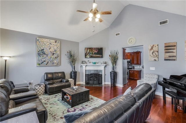 living room with dark wood finished floors, a tiled fireplace, visible vents, and ceiling fan