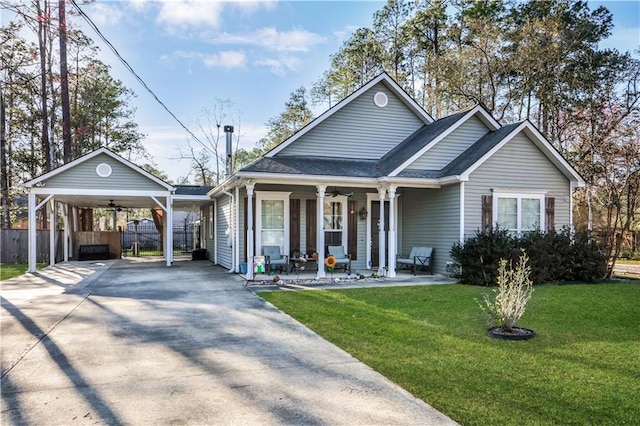 view of front facade with a front lawn, fence, concrete driveway, a carport, and ceiling fan