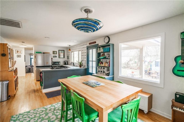 dining room with visible vents, baseboards, and light wood-style floors