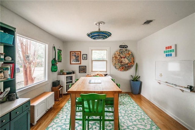 dining space with a wealth of natural light, visible vents, light wood-style flooring, and baseboards