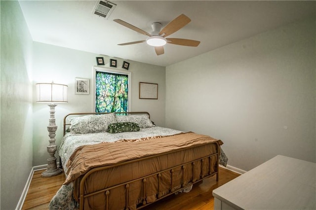 bedroom featuring visible vents, baseboards, dark wood-type flooring, and a ceiling fan