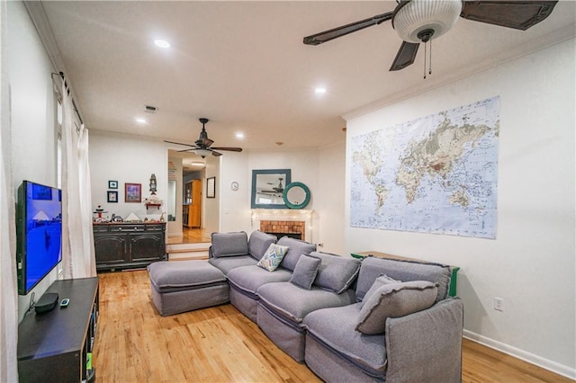 living area featuring baseboards, ceiling fan, recessed lighting, light wood-style flooring, and a fireplace