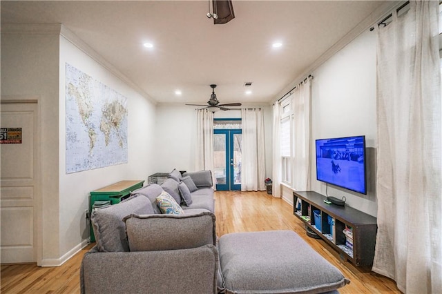 living area with ornamental molding, french doors, light wood finished floors, baseboards, and ceiling fan