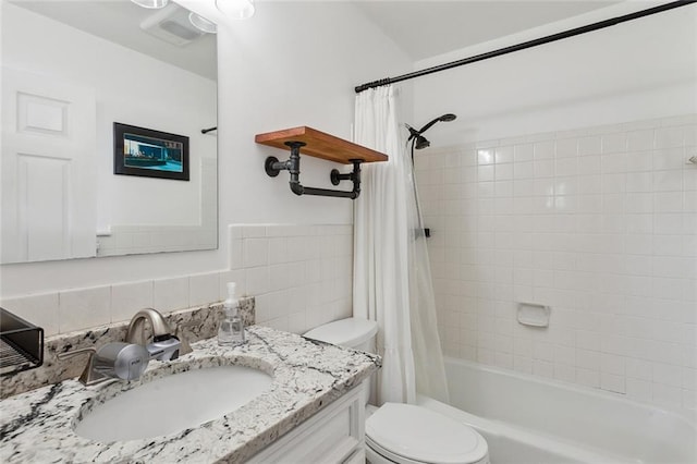 bathroom featuring vanity, tile walls, toilet, and shower / bath combo with shower curtain