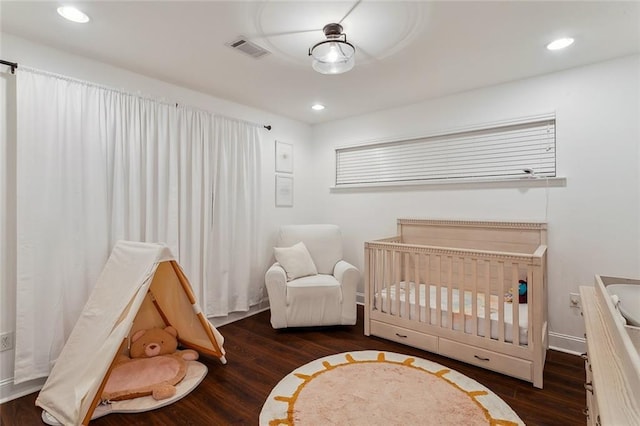 bedroom with visible vents, wood finished floors, recessed lighting, a nursery area, and baseboards