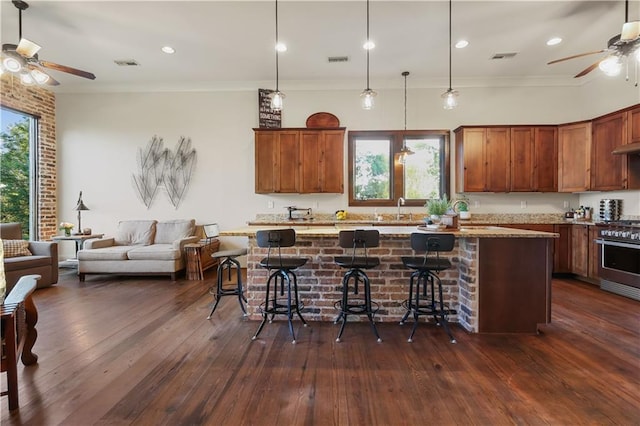 kitchen featuring visible vents, dark wood-type flooring, a sink, open floor plan, and stainless steel stove