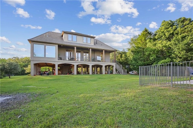 rear view of property featuring stairs, a balcony, a lawn, and stucco siding