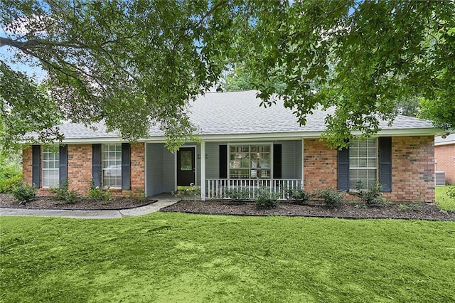 single story home featuring brick siding, roof with shingles, covered porch, and a front yard