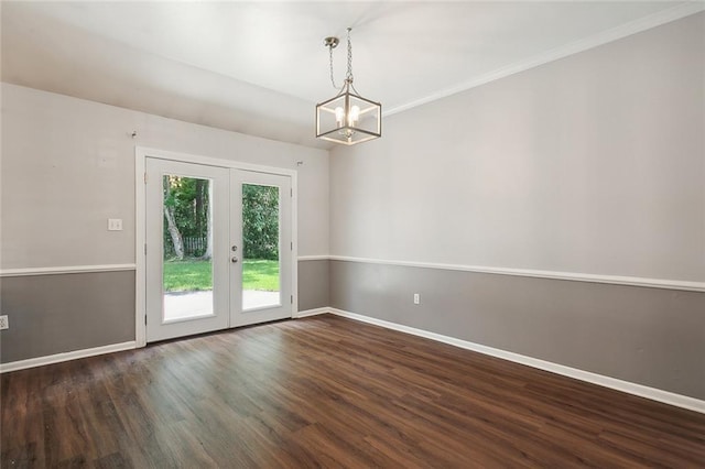 empty room featuring wood finished floors, french doors, an inviting chandelier, crown molding, and baseboards