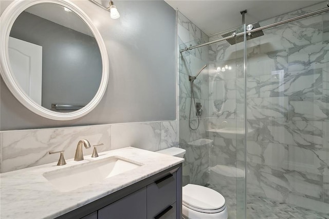 bathroom featuring a marble finish shower, toilet, vanity, and tile walls