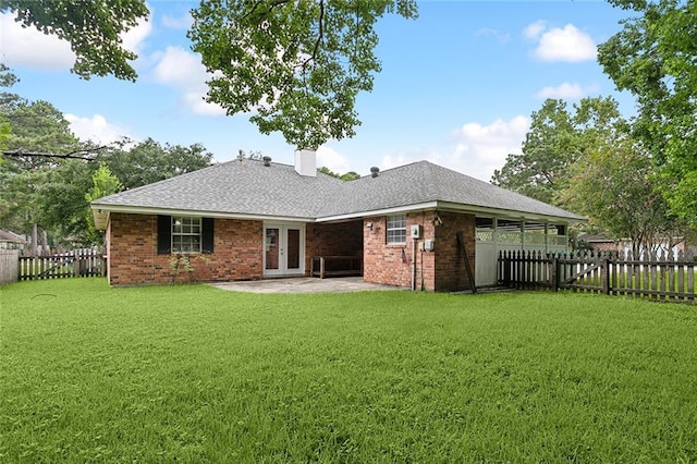 back of house featuring french doors, brick siding, a fenced backyard, and a yard